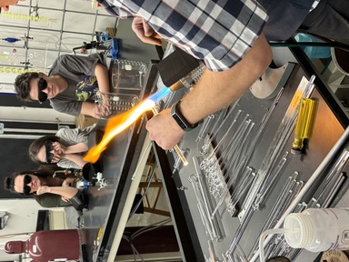 Students watch professor in glassblowing facility
