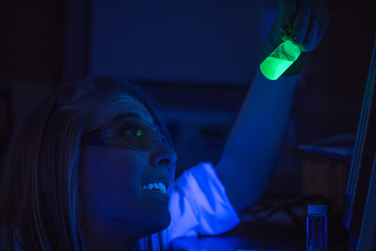woman holding glowing material doing nuclear research